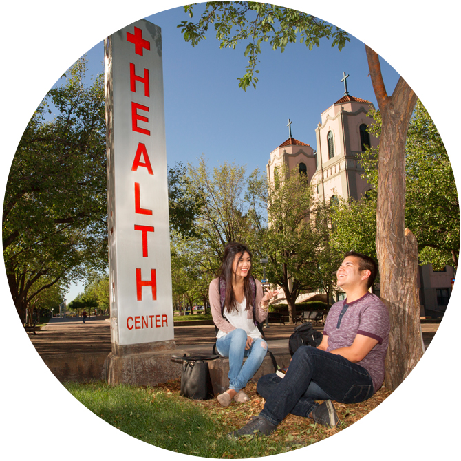 students sitting by health center sign